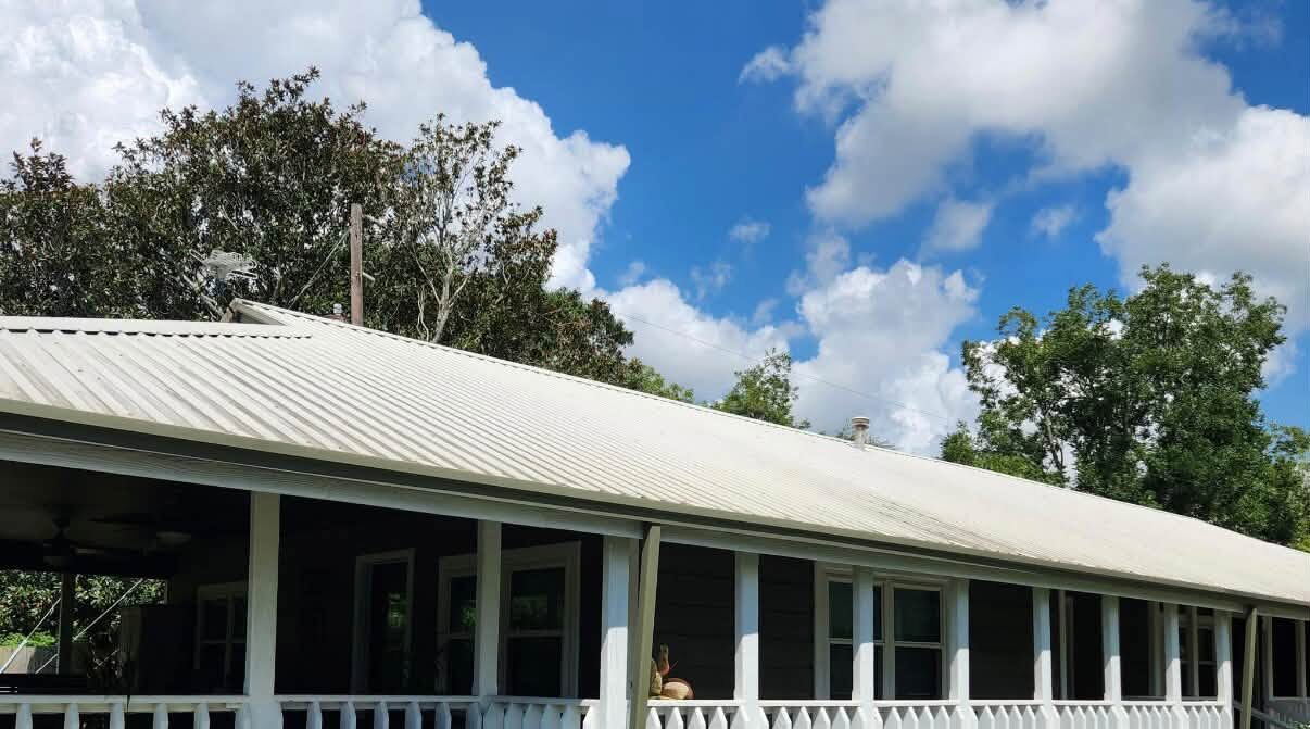 A long ranch house porch with the skirting boards green and the decking dull