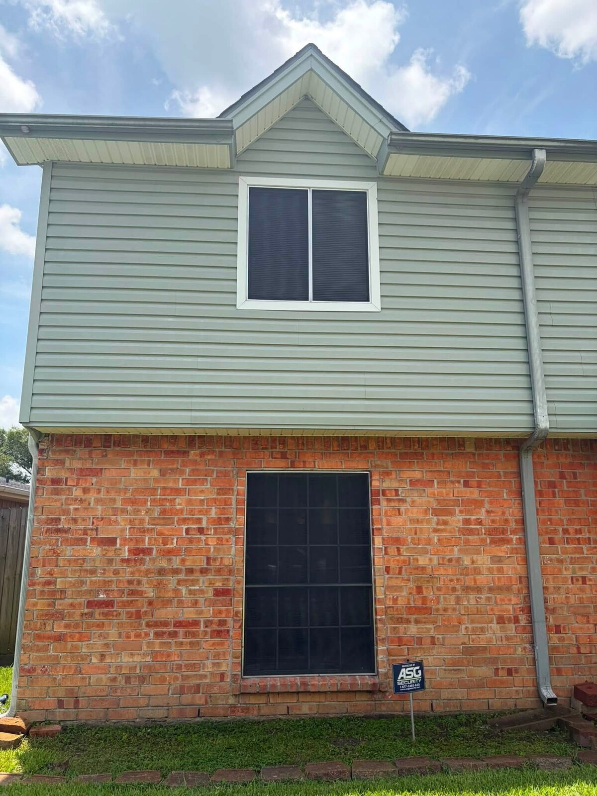The same siding washed clean, the panels back to an even pale green against bright brick